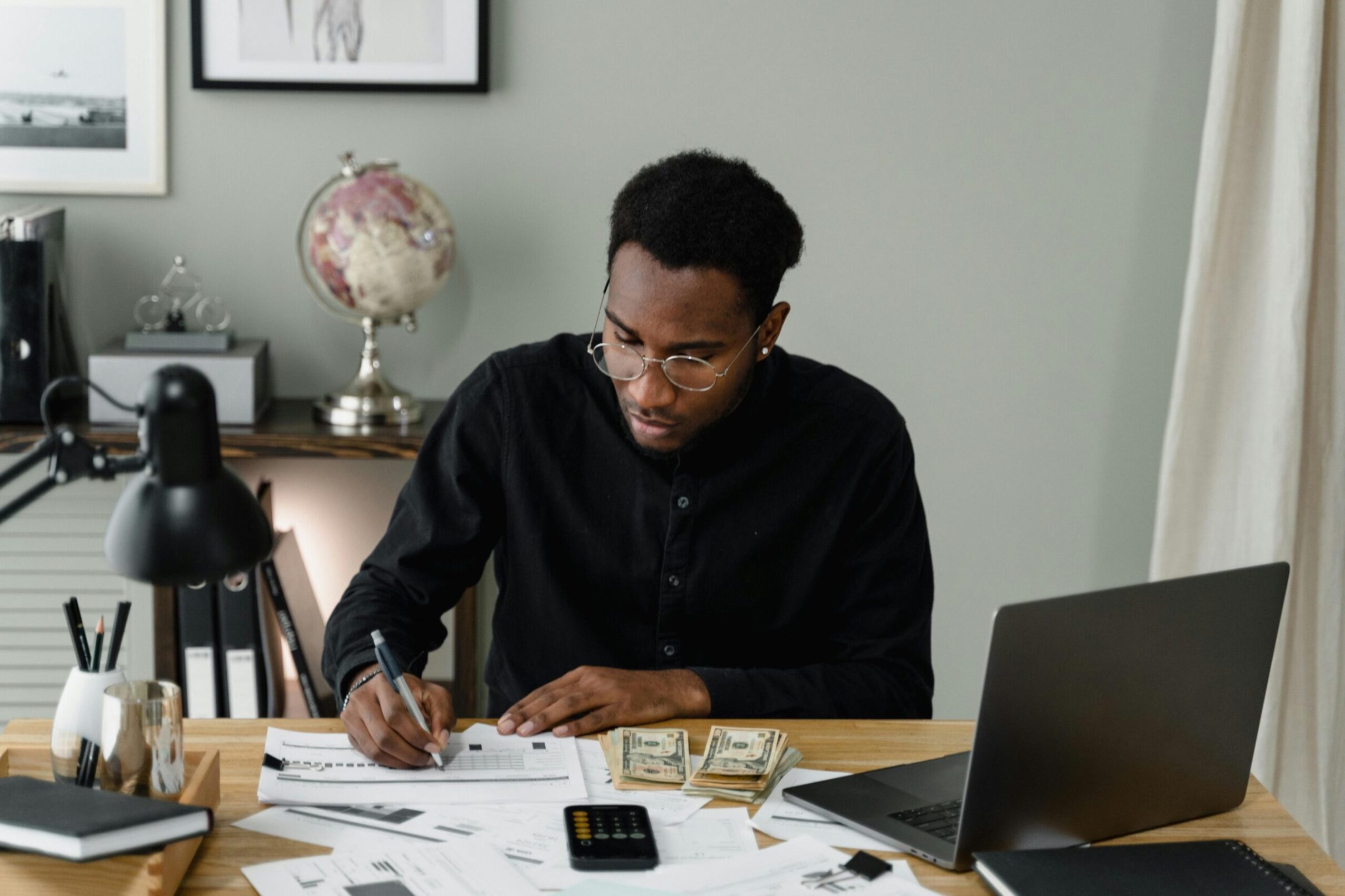 "A person managing their budget using a laptop and notes, symbolizing financial organization and saving money."