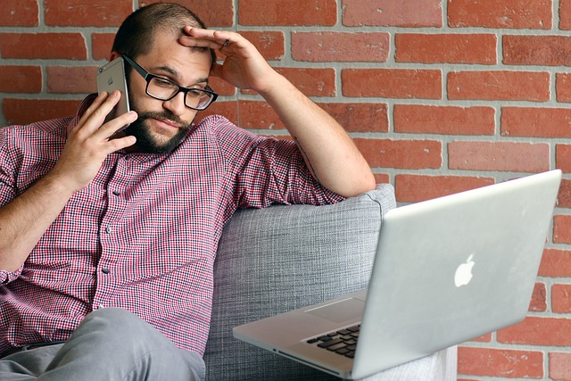 Managing stock market emotions: stressed person looking at laptop and speaking on the phone during volatile market conditions.