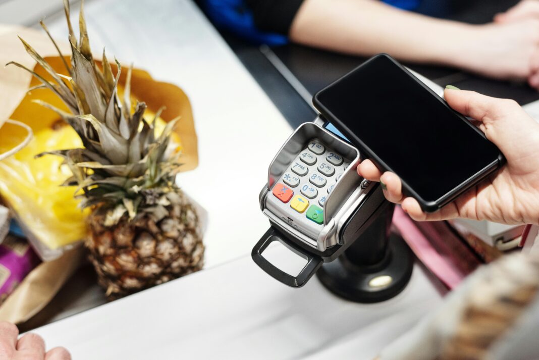 A pineapple on a counter next to a payment terminal, symbolizing the convenience of digital wallets for purchasing fresh produce.