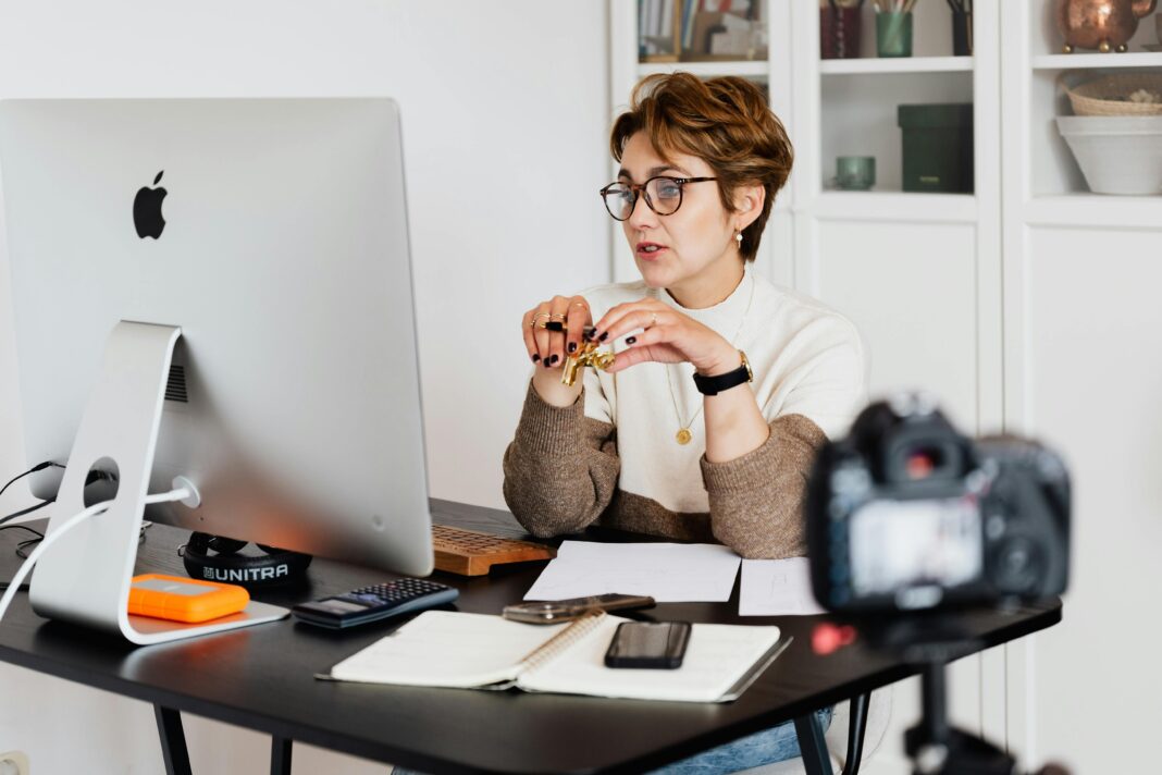 A woman sitting at a desk with her computer, teaching students online and showing how to make money as an online tutor.