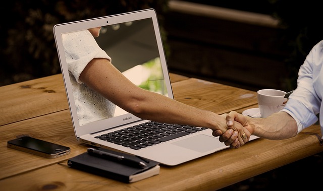 Handshake through laptop screens, representing collaboration to start a dropshipping store in 2025